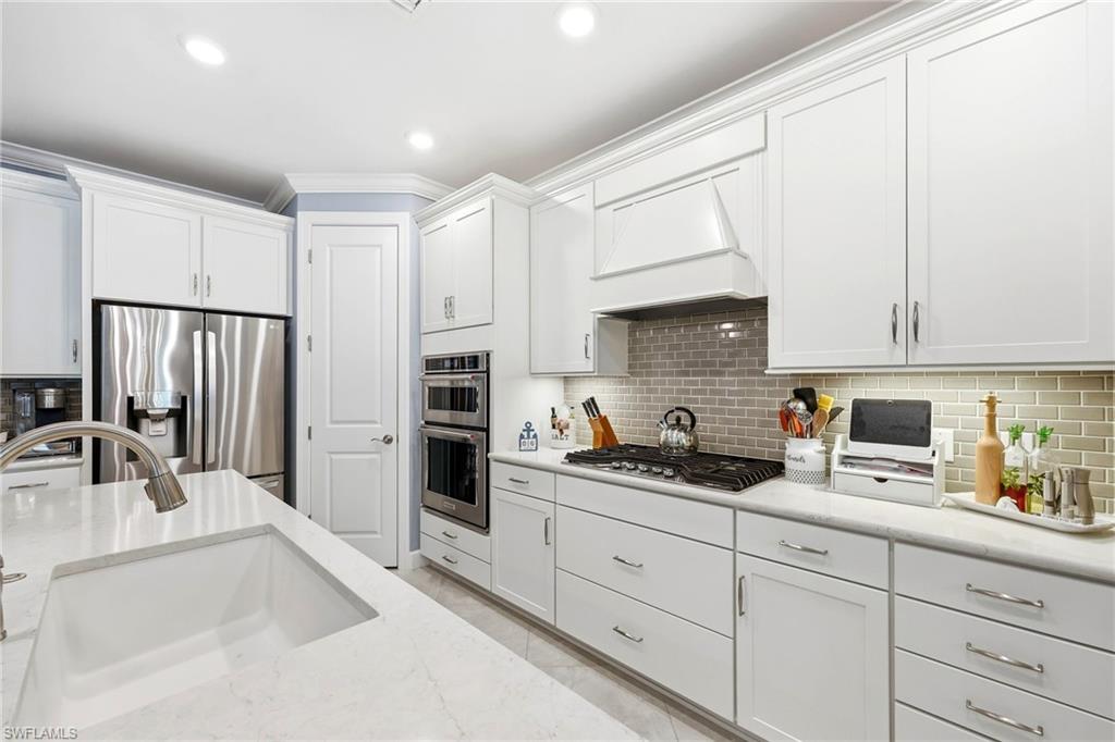 Kitchen featuring white cabinets, stainless steel appliances, ornamental molding, recessed lighting, and light stone countertops