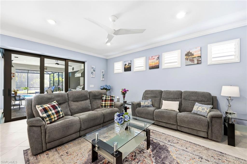 Living area with ceiling fan, plenty of natural light, crown molding, a sunroom, and tile patterned floors