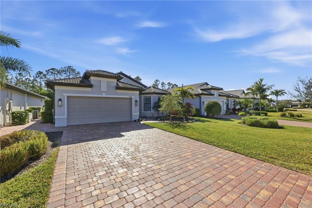 summerwood modelhome with a front lawn, decorative driveway, stucco siding, an attached garage, and a tile roof