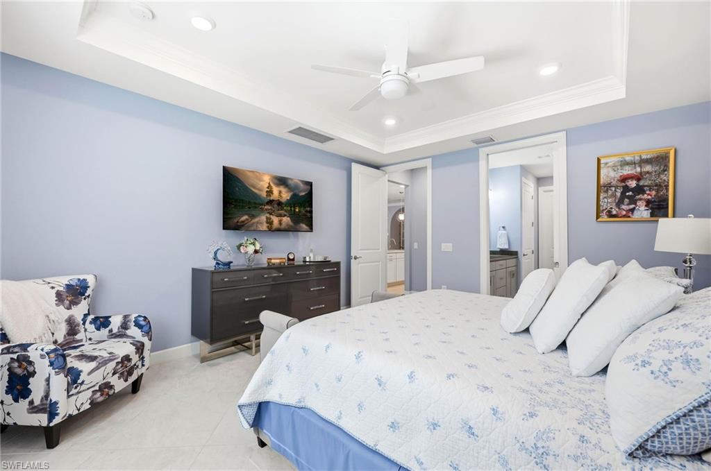 Bedroom featuring a raised ceiling, recessed lighting, ornamental molding, ceiling fan, and ensuite bathroom