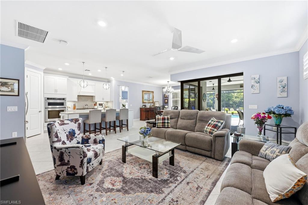 Living area with ornamental molding, hanging lights, and light tile patterned floors