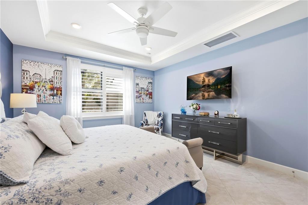 Bedroom with crown molding, recessed lighting, ceiling fan, light tile patterned flooring, and a tray ceiling