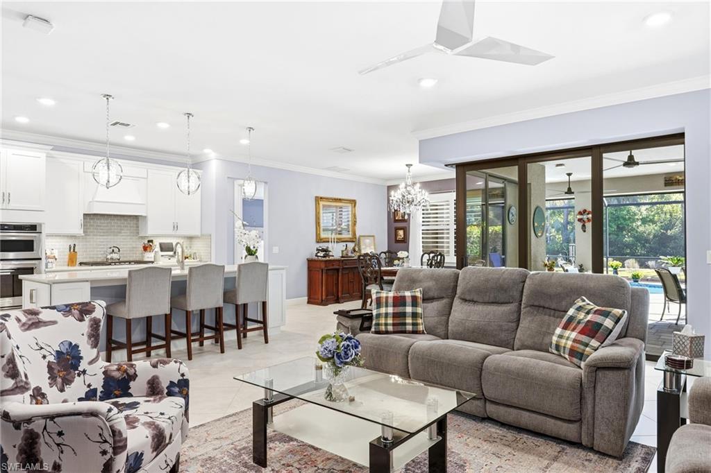 Living room featuring crown molding, suspended lighting, and light tile patterned floors