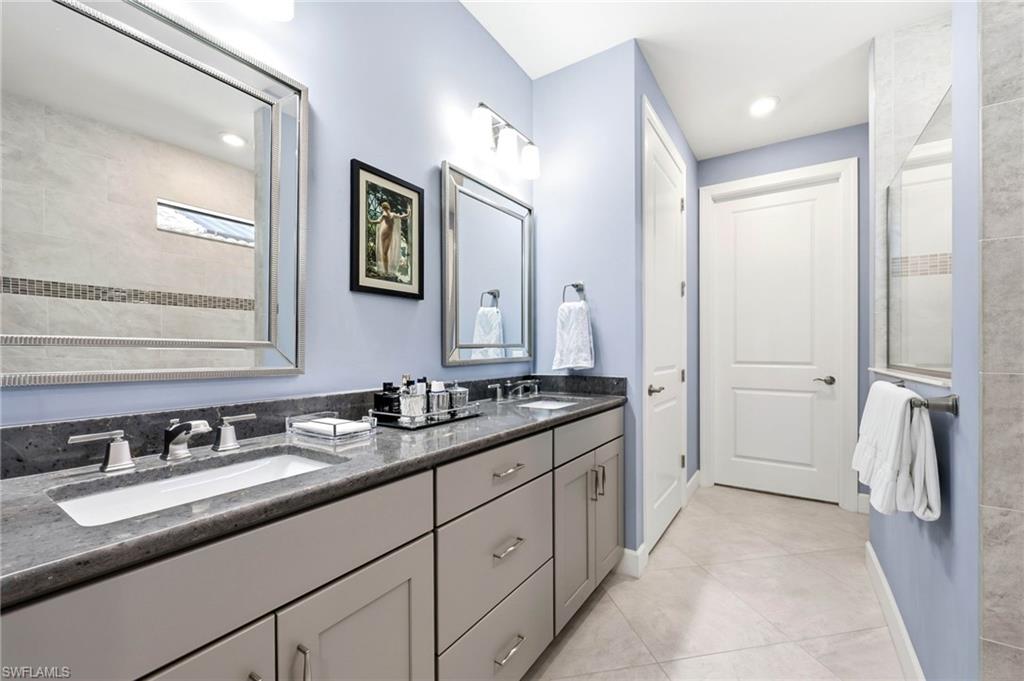 Full bath with double vanity, light tile patterned flooring, recessed lighting, and a tile shower