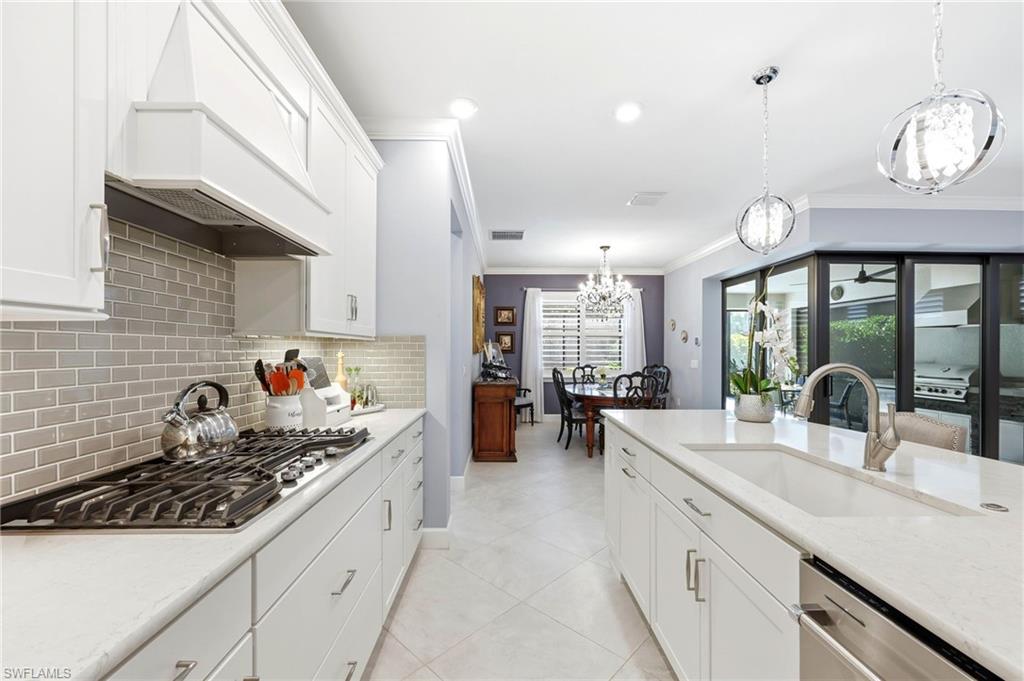 Kitchen featuring white cabinetry, light stone counters, stainless steel appliances, and ornamental molding