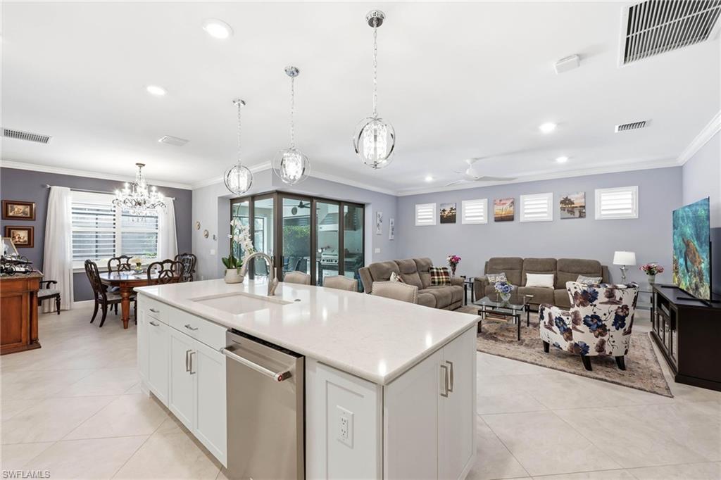 Kitchen with white cabinetry, stainless steel dishwasher, crown molding, a chandelier, and an island with sink