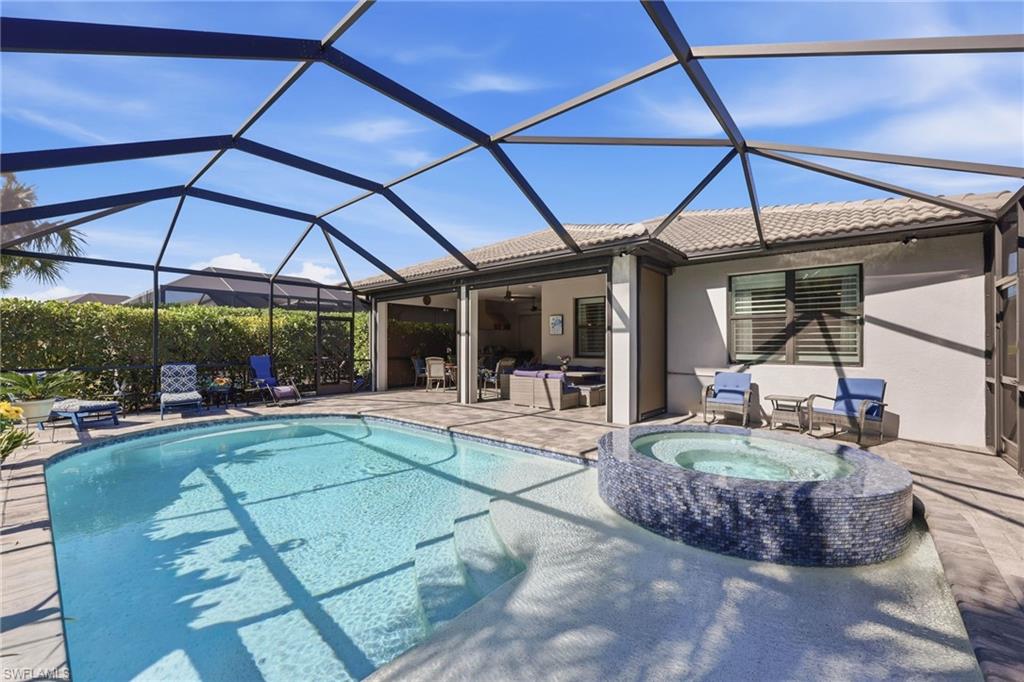 Combined pool / hot tub featuring a sunroom, glass enclosure, and a patio