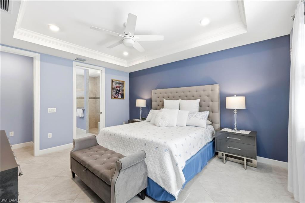 Bedroom featuring a tray ceiling, recessed lighting, ceiling fan, connected bathroom, and crown molding