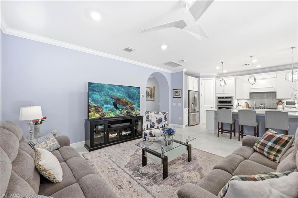 Living room featuring crown molding, arched walkways, recessed lighting, and light tile patterned flooring