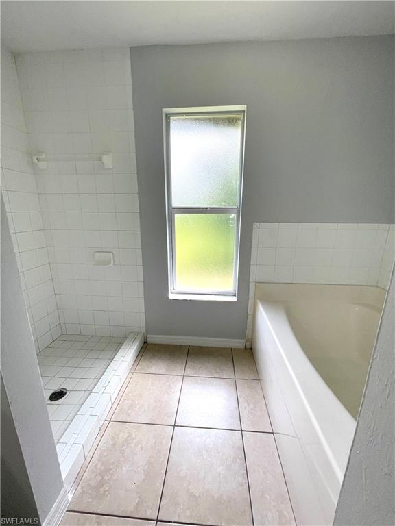 Full bath featuring light tile patterned floors, a shower stall, and a bath