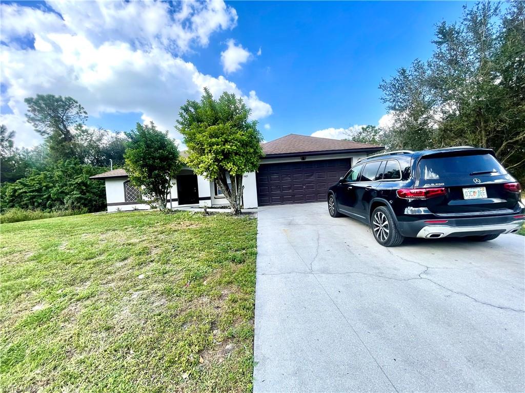 Obstructed view of property with concrete driveway, a front lawn, and an attached garage