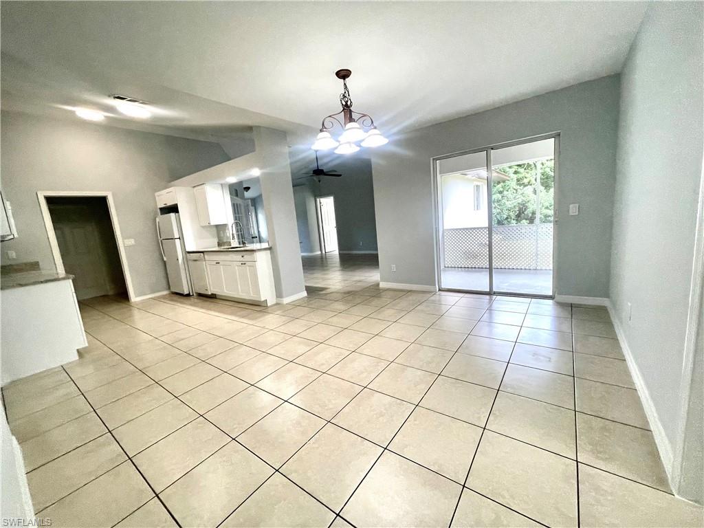 Unfurnished dining area with light tile patterned flooring, hanging lights, and ceiling fan