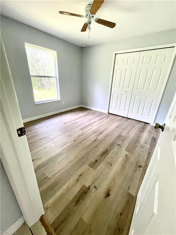 Unfurnished bedroom with a ceiling fan, a closet, and light wood-style flooring