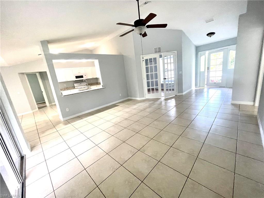 Unfurnished living room featuring lofted ceiling, light tile patterned floors, and ceiling fan