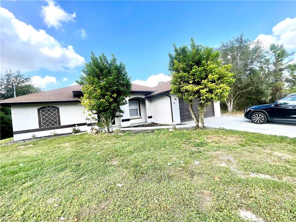 View of front of property featuring stucco siding, an attached garage, a front lawn, and concrete driveway