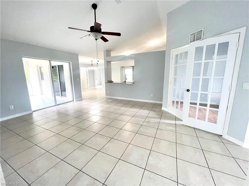 Empty room with light tile patterned floors, a ceiling fan, and french doors