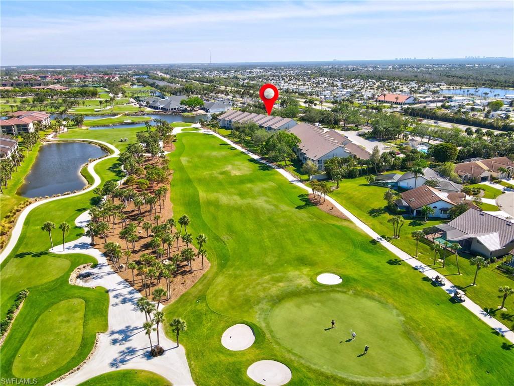 Aerial view of property and surrounding area featuring nearby suburban area, a large body of water, and a golf course