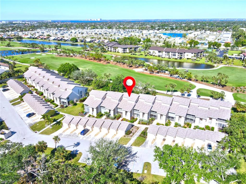 Aerial view of property's location with a local golf course, a large body of water, and nearby suburban area