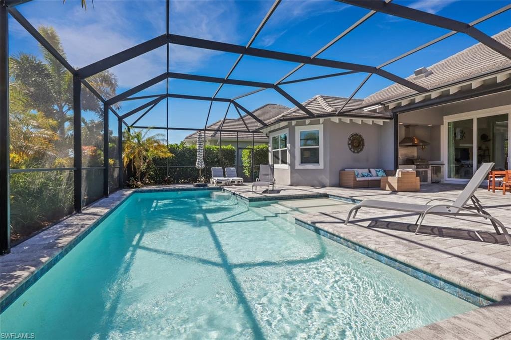 View of pool featuring a lanai, a sunroom, patio surround, and an outdoor hangout area