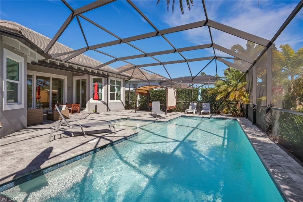 Outdoor pool with glass enclosure, a sunroom, and a patio area