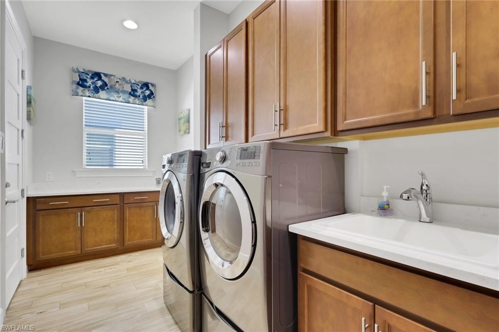 Laundry room featuring cabinet space, washer and clothes dryer, light wood-style flooring, and recessed lighting