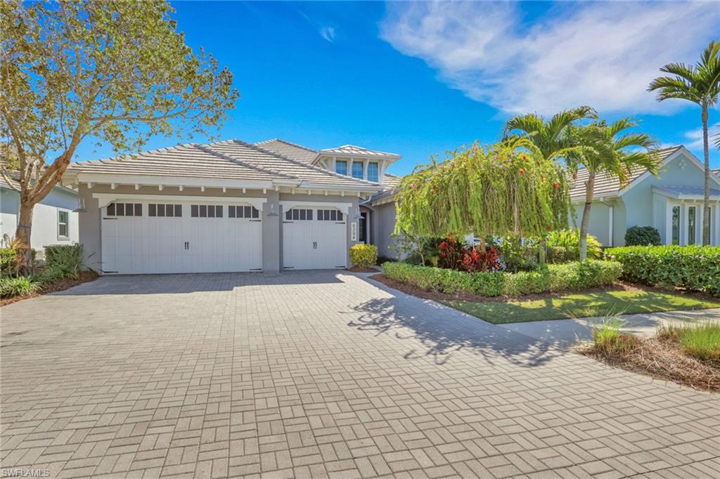 View of front facade with stucco siding, decorative driveway, a tile roof, and a garage