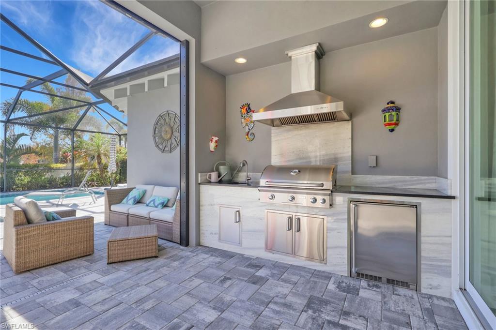 View of patio with an outdoor kitchen and area to lounge, glass enclosure, a sunroom, and an outdoor pool