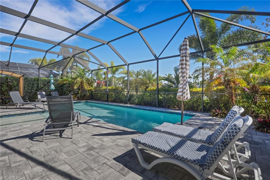 Outdoor pool featuring glass enclosure, a patio, and a sunroom