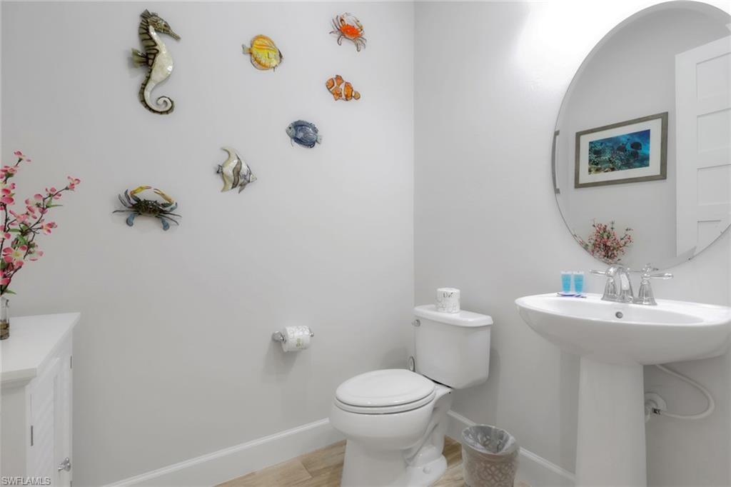 Half bathroom with toilet and wood finished floors