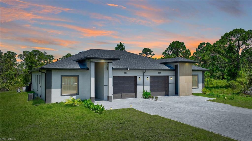View of front of house featuring a yard, a garage, decorative driveway, and roof with shingles