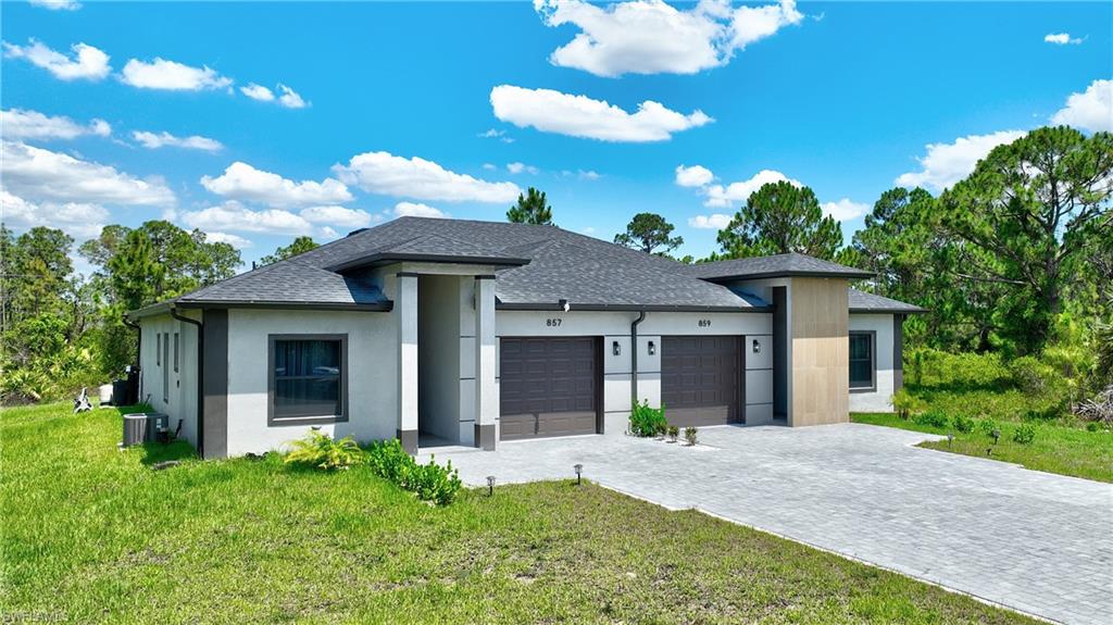 View of front of property with an attached garage, roof with shingles, a front lawn, and decorative driveway