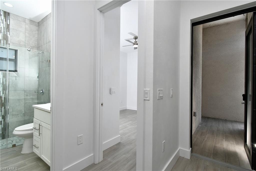 Bathroom with a shower stall, vanity, light wood-type flooring, and a ceiling fan