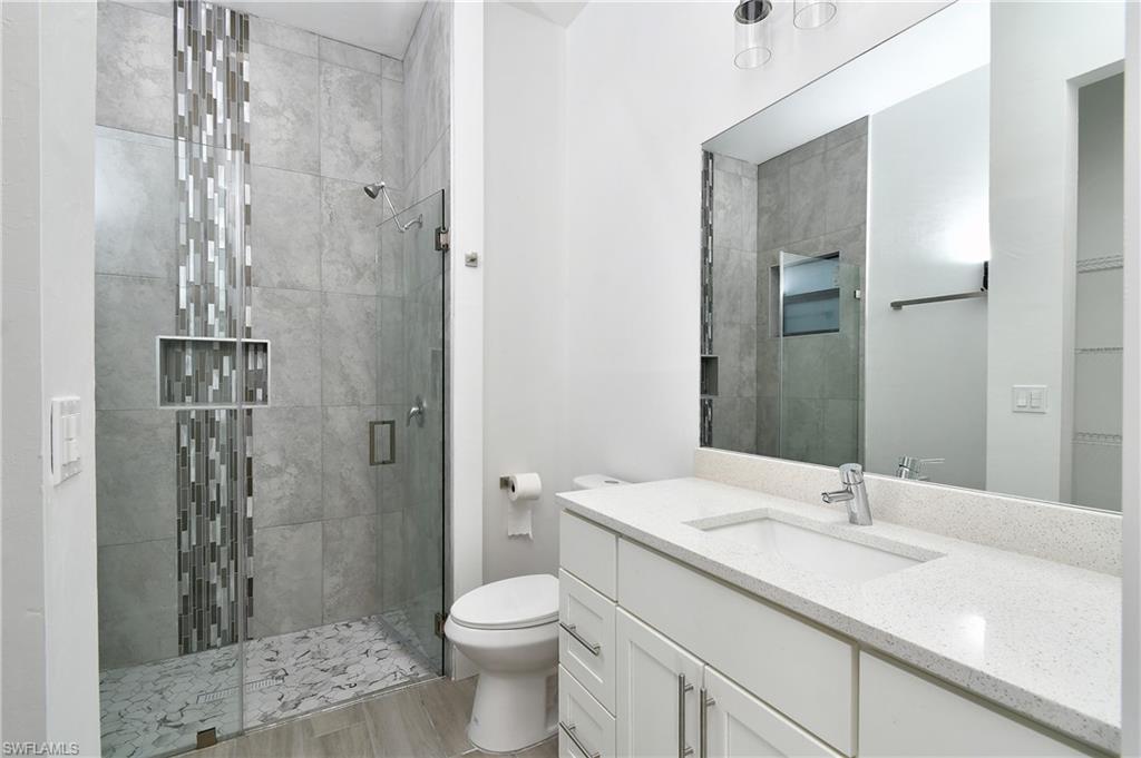 Bathroom with a shower stall, vanity, a walk in closet, and light wood-style flooring