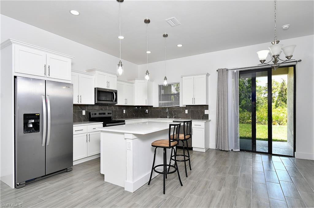 Kitchen with stainless steel appliances, white cabinetry, a kitchen breakfast bar, a kitchen island, and decorative backsplash