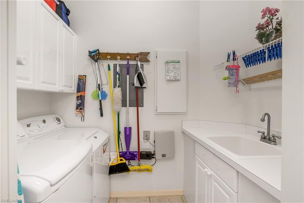 Laundry room with washer and dryer, sink, light tile patterned floors, and cabinets