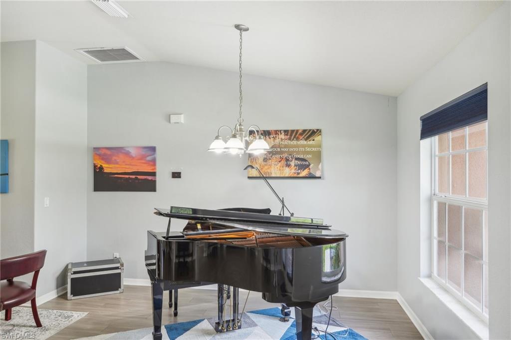 Living area featuring vaulted ceiling, light wood-style flooring, and hanging lights