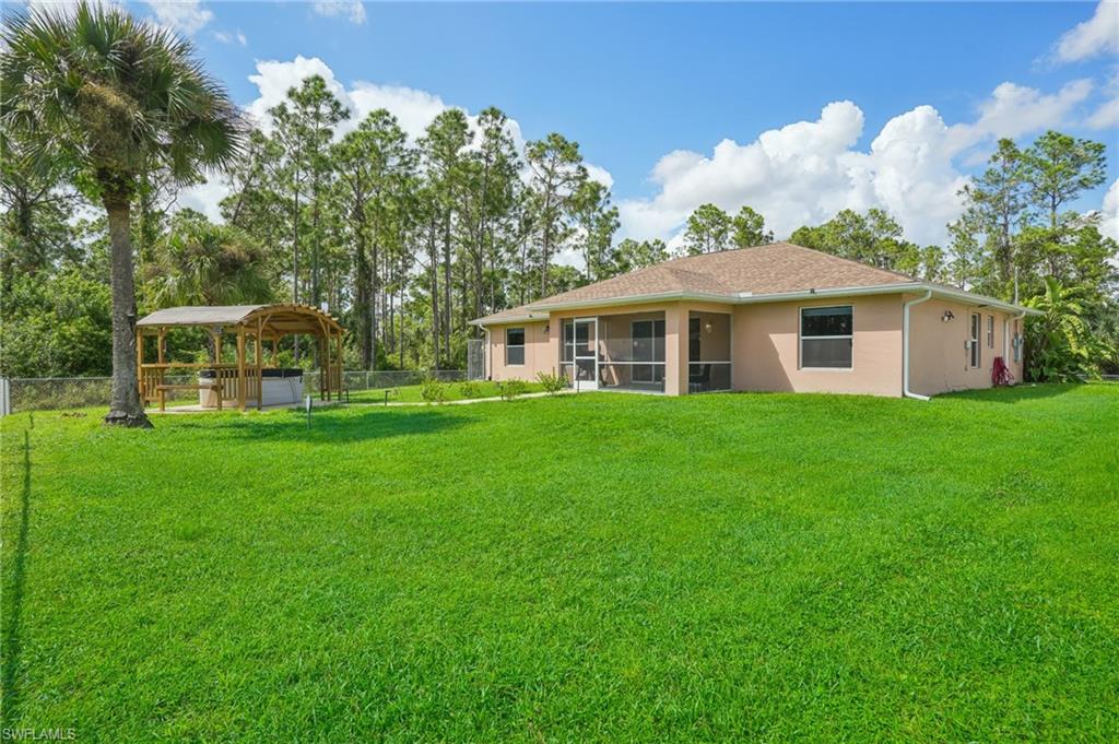 Rear view of property featuring stucco siding, a sunroom, and a hot tub