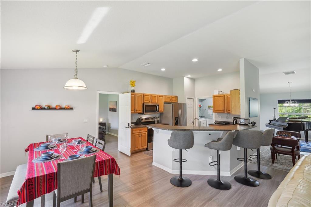 Kitchen featuring pendant lighting, a kitchen breakfast bar, a peninsula, light wood-style floors, and vaulted ceiling