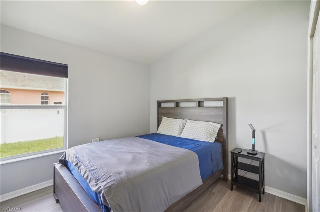 Bedroom with wood finished floors and lofted ceiling