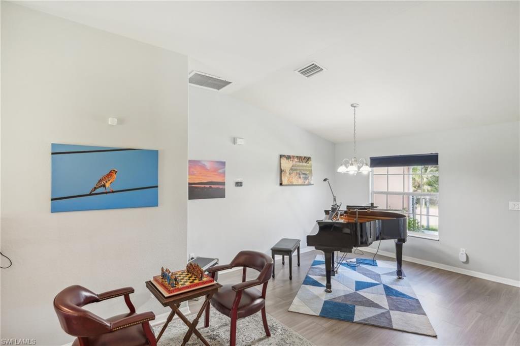 Sitting room with lofted ceiling, light wood-style flooring, and hanging lights