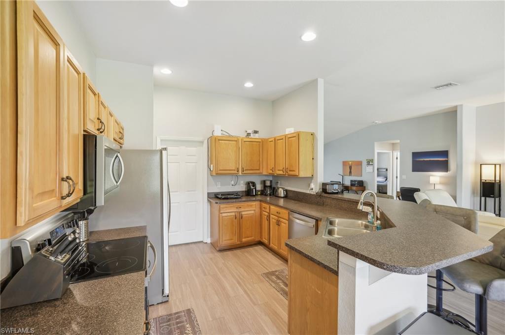 Kitchen featuring a peninsula, light wood-style floors, a kitchen breakfast bar, open floor plan, and stainless steel appliances