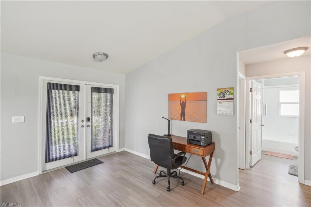 Home office with french doors, light wood finished floors, and lofted ceiling