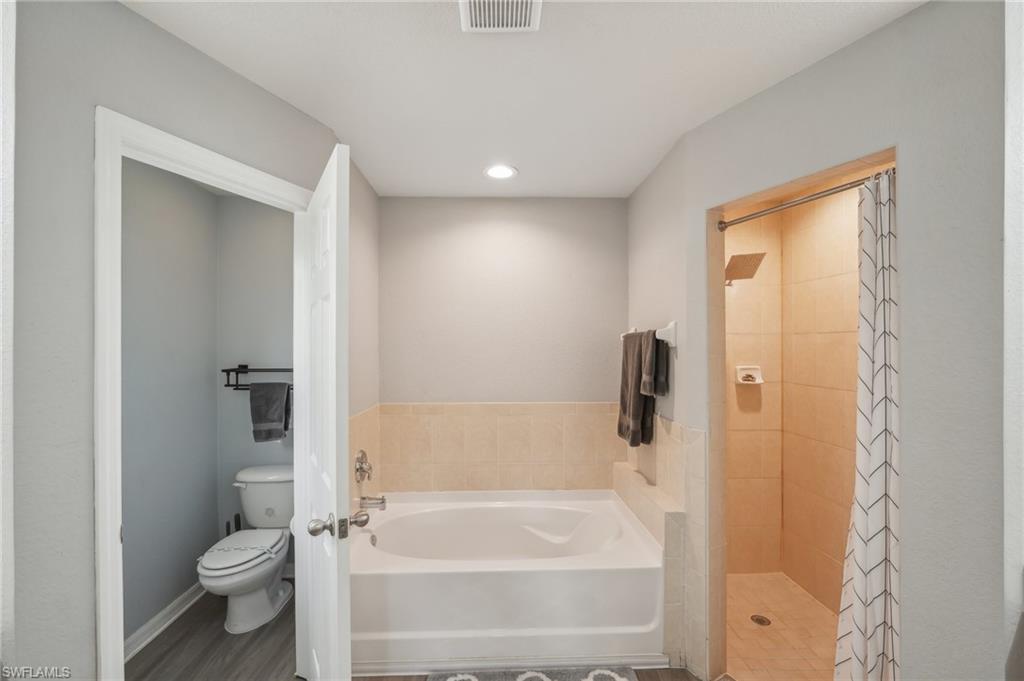 Full bath featuring a garden tub, a shower stall, recessed lighting, and wood finished floors
