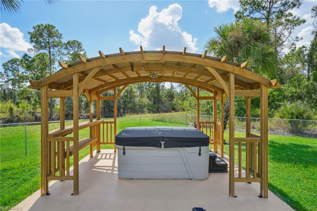 Fenced backyard featuring a patio, a hot tub, and view of wooded area