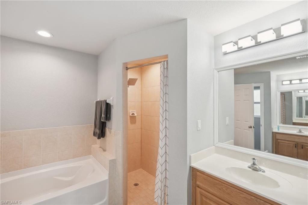 Full bathroom featuring vanity, a stall shower, a bath, and recessed lighting