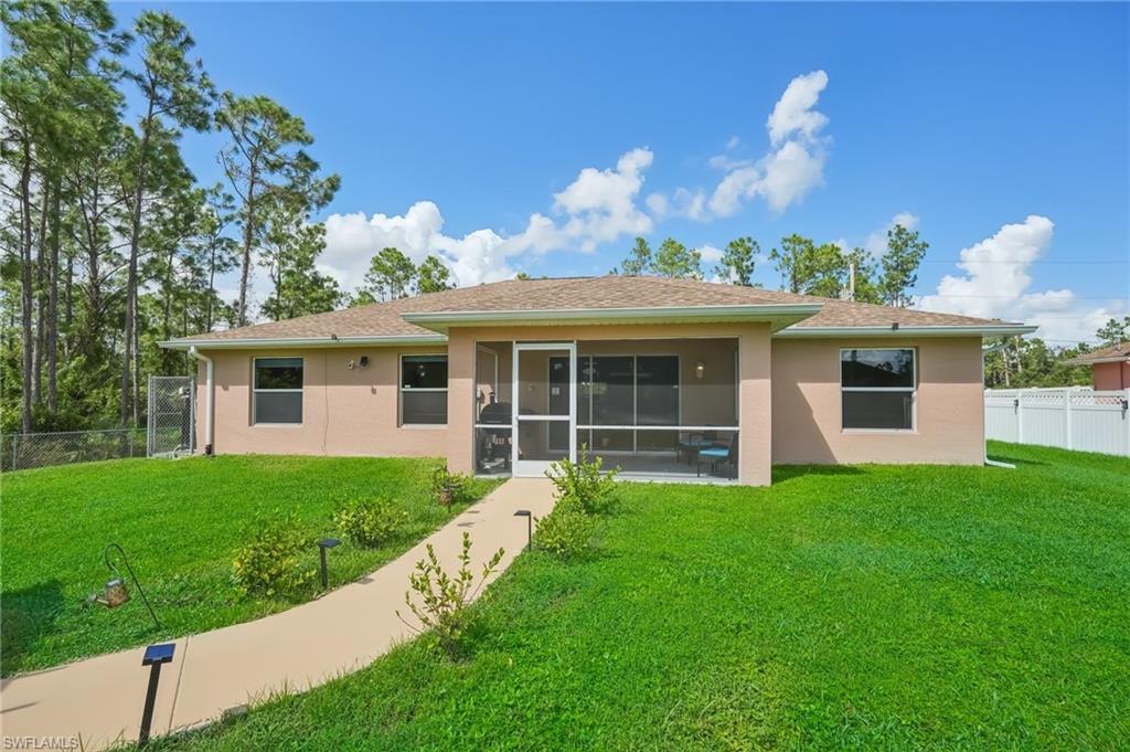 Back of house featuring a fenced backyard, stucco siding, a sunroom, and roof with shingles