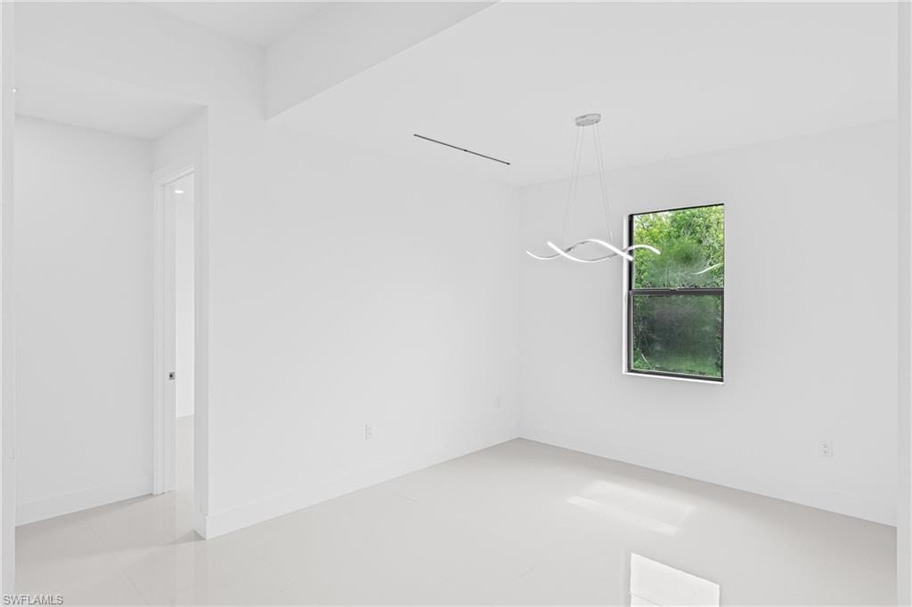 Empty room featuring baseboards and a chandelier