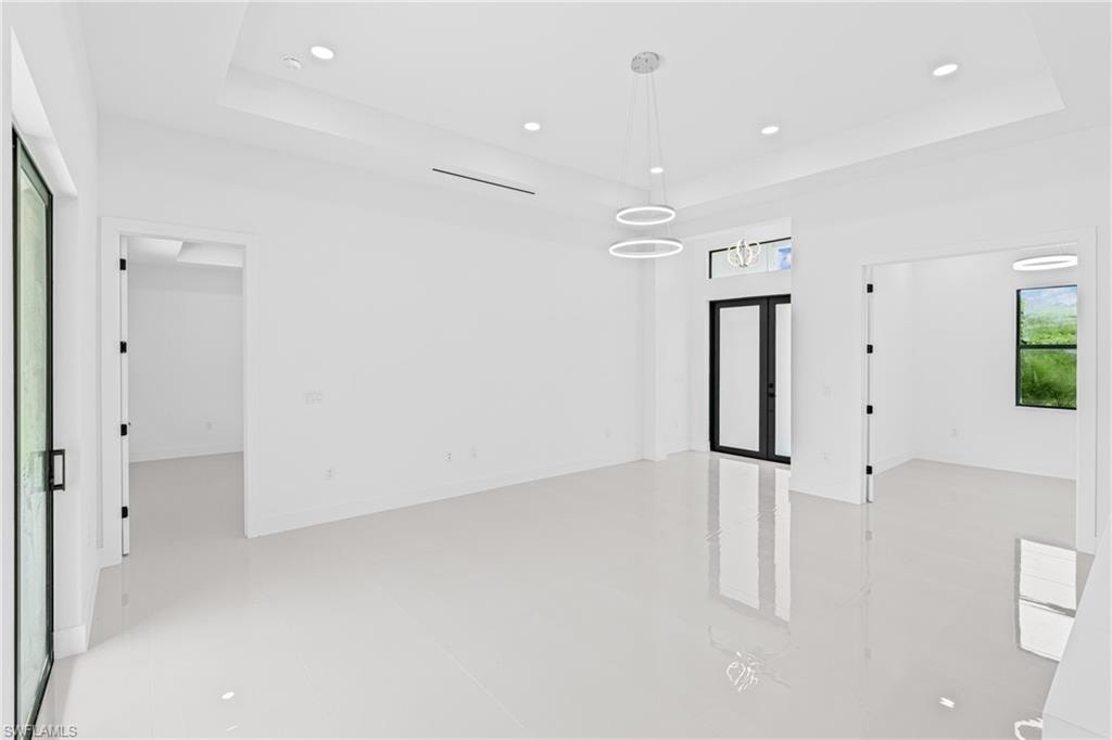 Unfurnished room featuring a tray ceiling, recessed lighting, and french doors