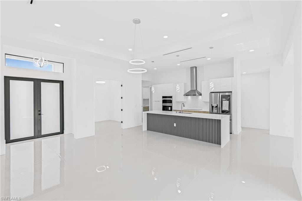 Kitchen with modern cabinets, a large island, decorative light fixtures, open floor plan, and white cabinetry