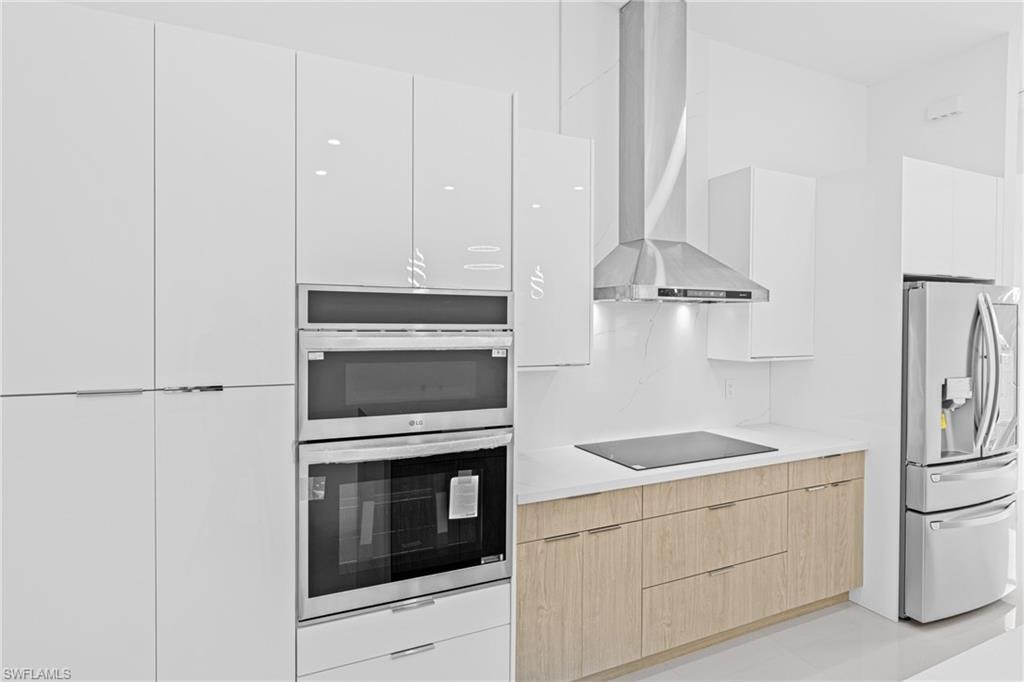 Two tone kitchen with modern cabinets, stainless steel appliances, two tone color scheme, and backsplash